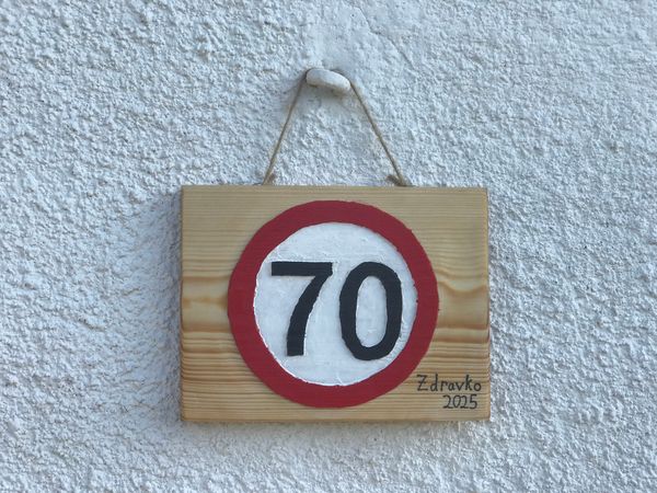 Lesen prometni znak za sedemdeseti rojstni dan, ki visi na fasadi hiše.